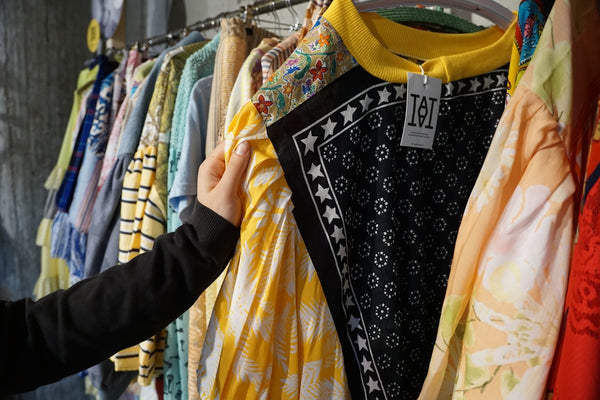 A hand selecting clothes from a rack in a store.