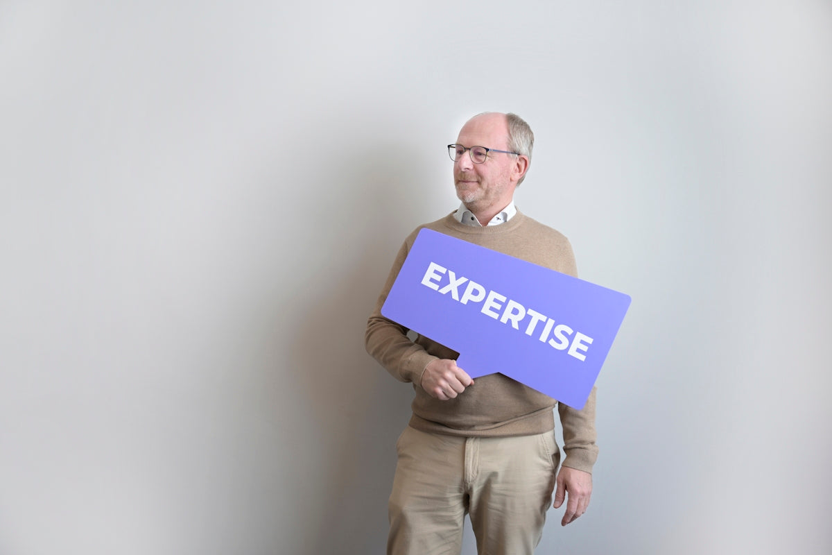 Man holding an expertise sign looking left.