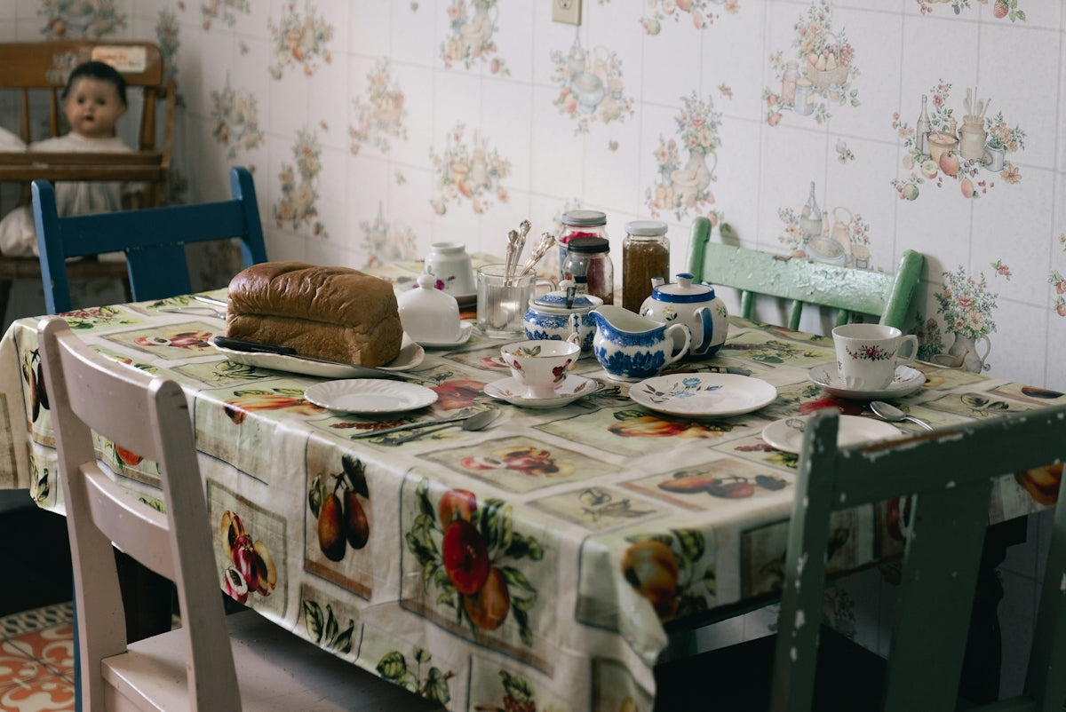 Breakfast table with bread, teacups, and floral tablecloth