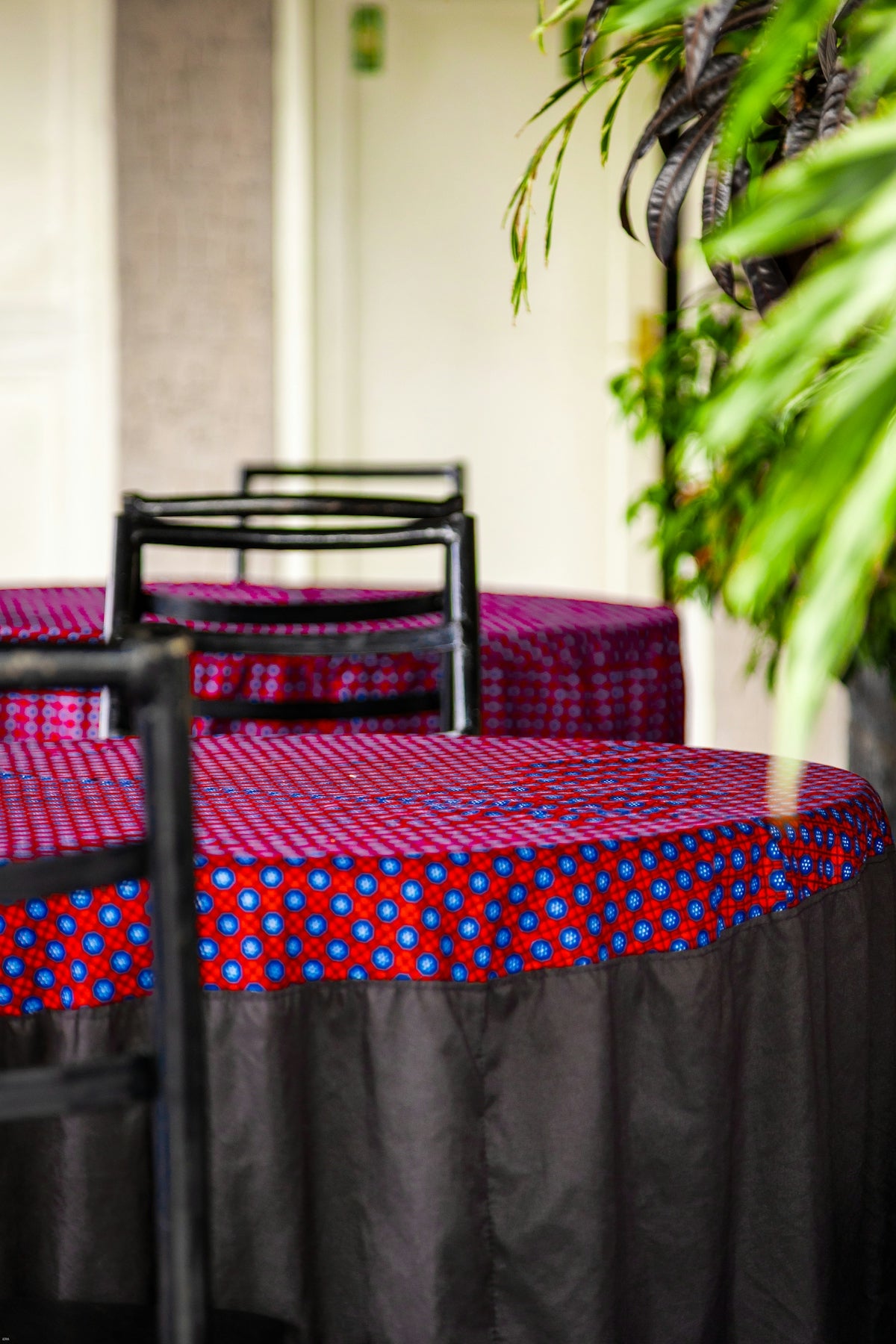 Tables with red and blue patterned tablecloths and black chairs