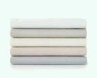 Stack of folded percale fitted sheets in neutral colours