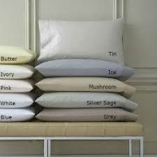 Stack of percale pillowcases in soft neutral colours on a bench