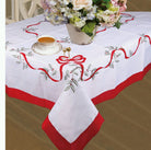 White Christmas tablecloth with a red satin border, embroidered red ribbon bow and holly berries