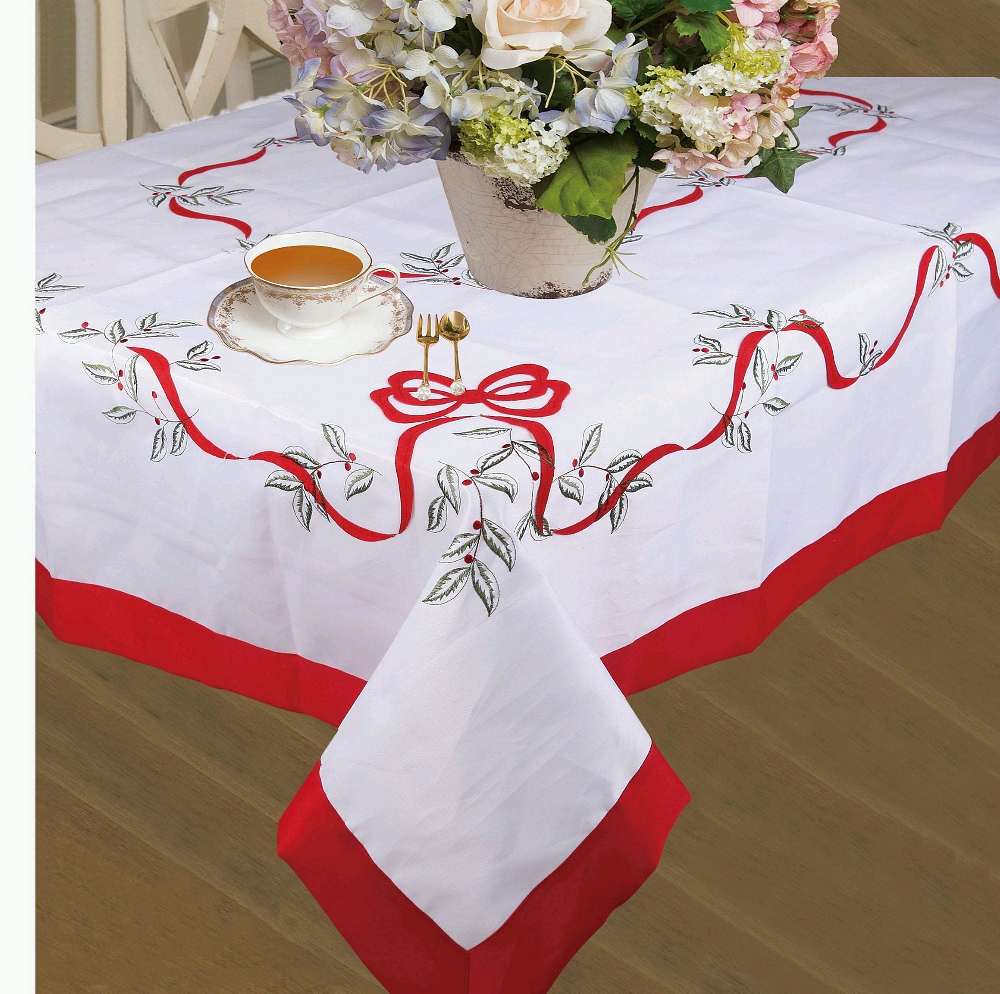 White Christmas tablecloth with a red satin border, embroidered red ribbon bow and holly berries