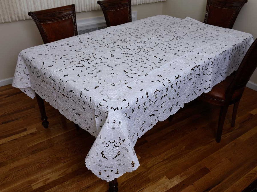 White cutwork tablecloth hand-embroidered with grapes and vine leaves in relief, with a scalloped edge