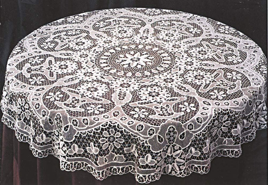 White openwork lace tablecloth with a central rosette medallion and deep scalloped border on a dark surface