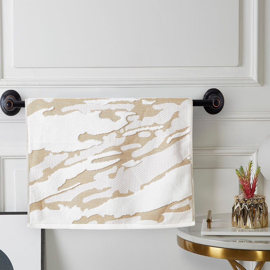 Gold and white woven terry hand towel with a cloudy marbled jacquard, on a black towel bar