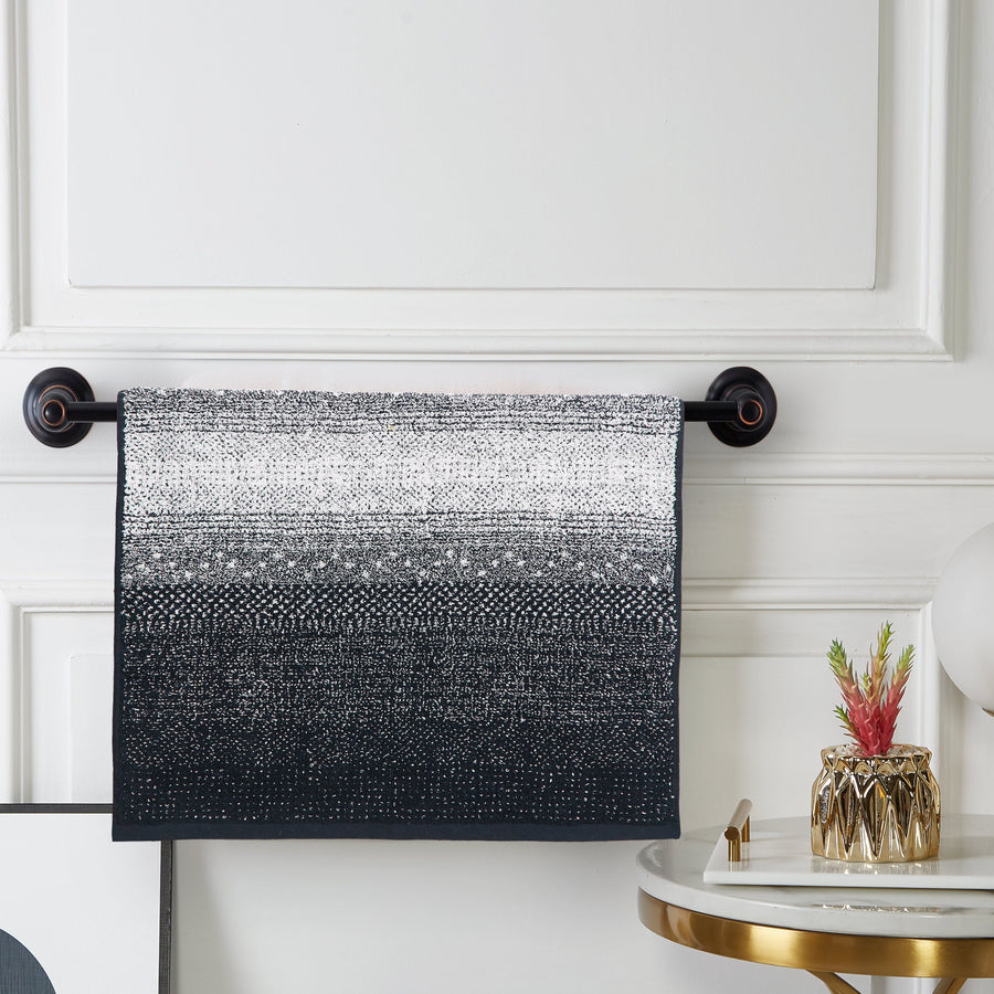 Ombré terry hand towel shading from white to black, hanging on a black towel bar