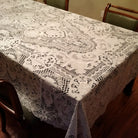 White embroidered lace tablecloth with dense floral openwork on a formal dining table