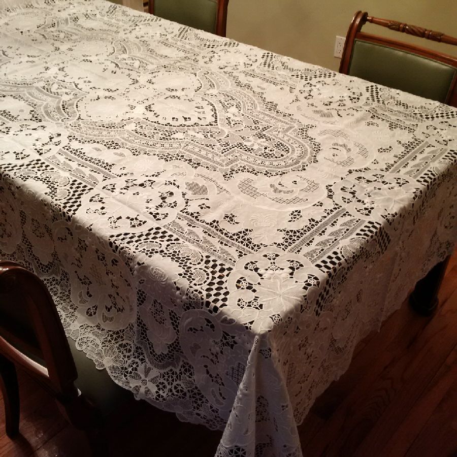 White embroidered lace tablecloth with dense floral openwork on a formal dining table