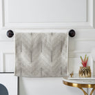 Grey and white chevron terry hand towel hanging on a black towel bar
