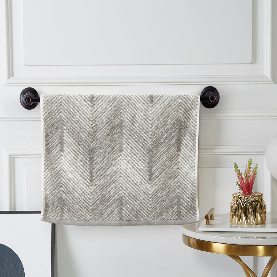 Grey and white chevron terry hand towel hanging on a black towel bar