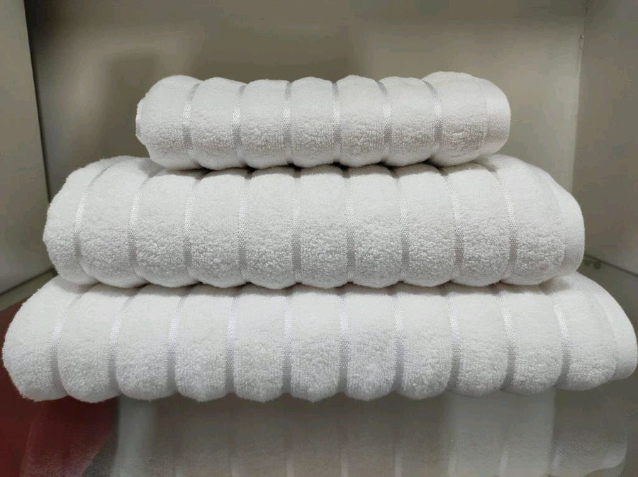 Stack of white terry towels with a raised ribbed stripe texture woven into the pile