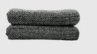 Folded black terry towels with a diagonal ribbed weave