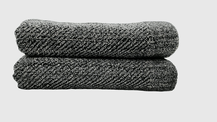 Folded black terry towels with a diagonal ribbed weave