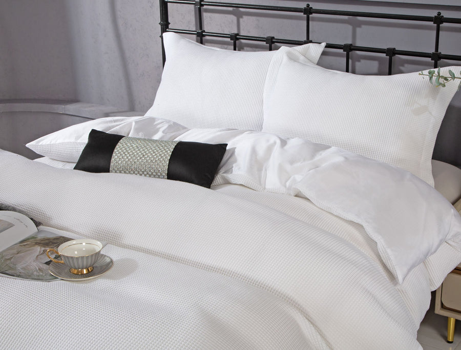 White waffle-textured cotton sateen duvet set with matching shams on a metal bed