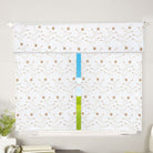 White sheer window curtain and valance embroidered with gold floral vines and a pompom trim