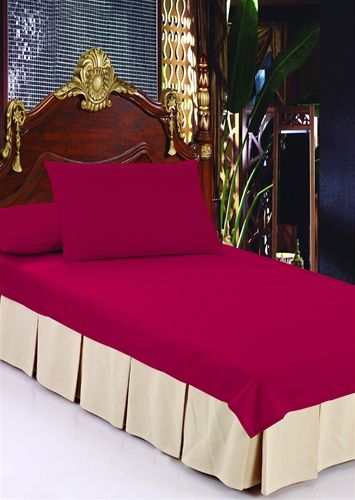 Sand box-pleat tailored bed skirt beneath a red fitted sheet on a bed