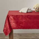 Burgundy damask tablecloth with tone-on-tone rose scrollwork and a scalloped edge on a dining table