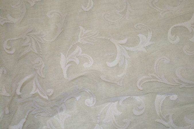 Elegant sheer fabric with intricate floral patterns in soft white tones.