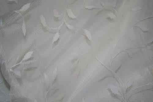 White Embroidered Fabric featuring delicate leaf patterns and a soft texture.